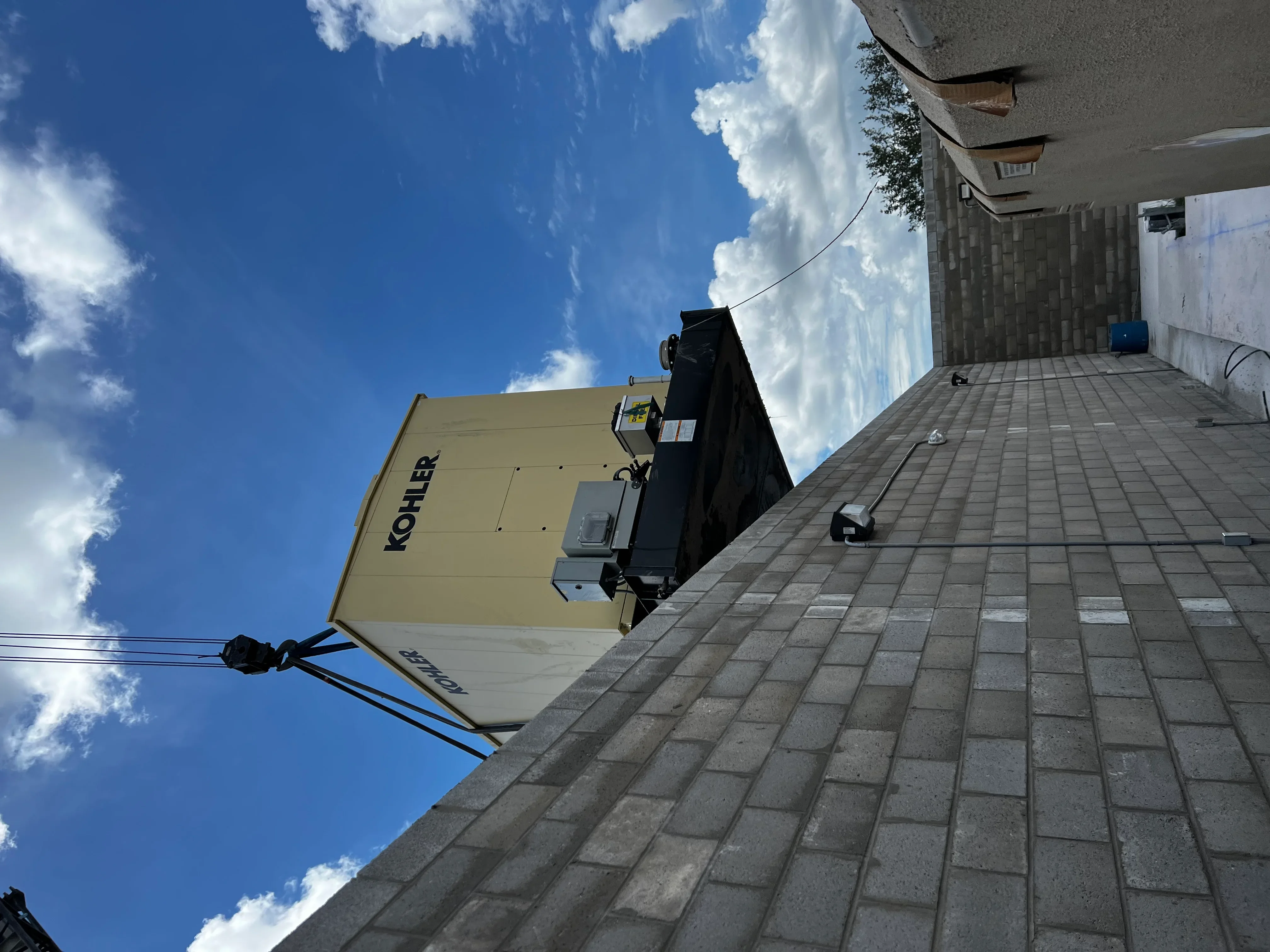 Kohler diesel generator installed on commercial rooftop with paver surface and building structure