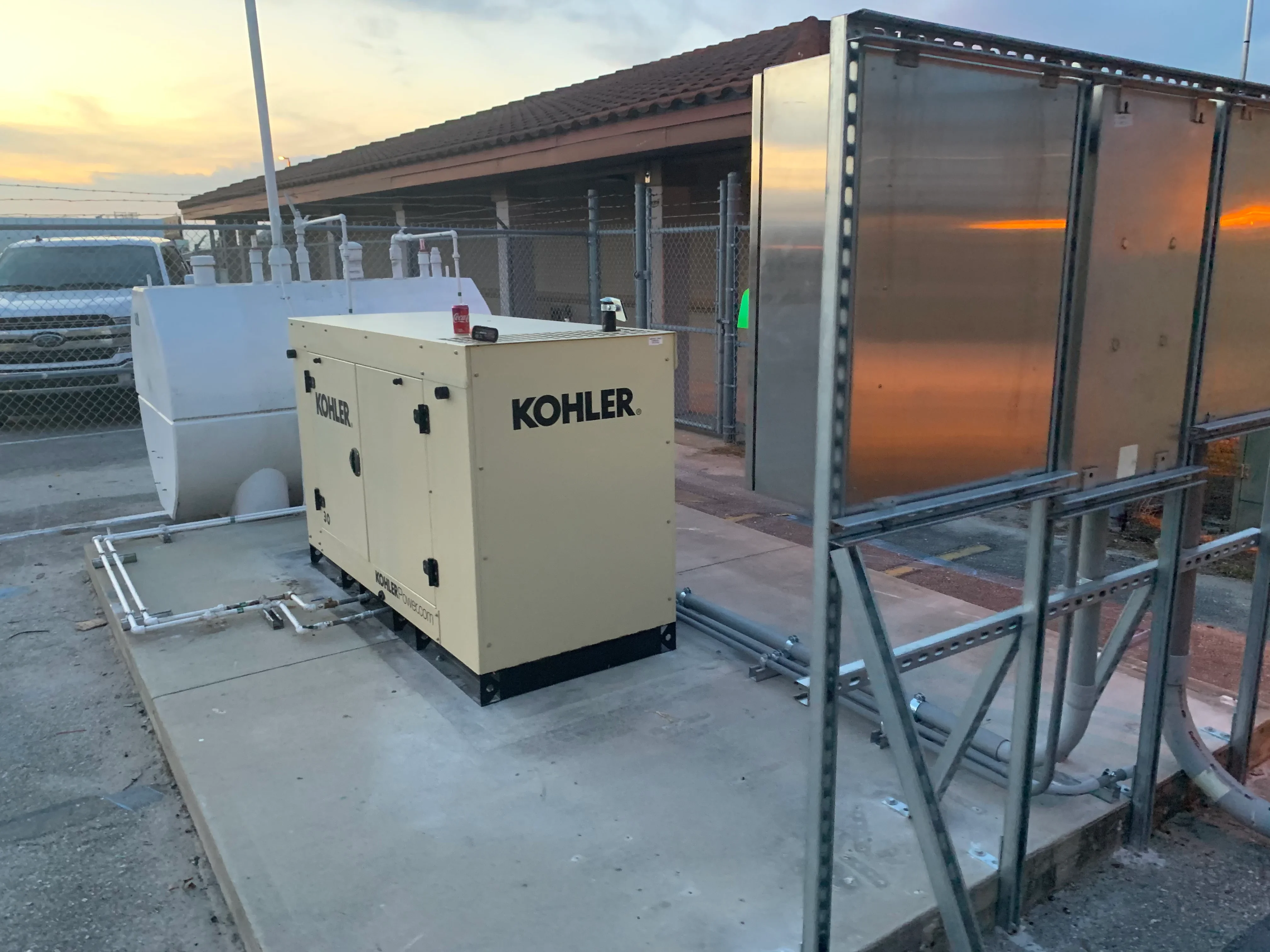 Kohler diesel generator with steel frame enclosure and translucent protective panels on concrete foundation
