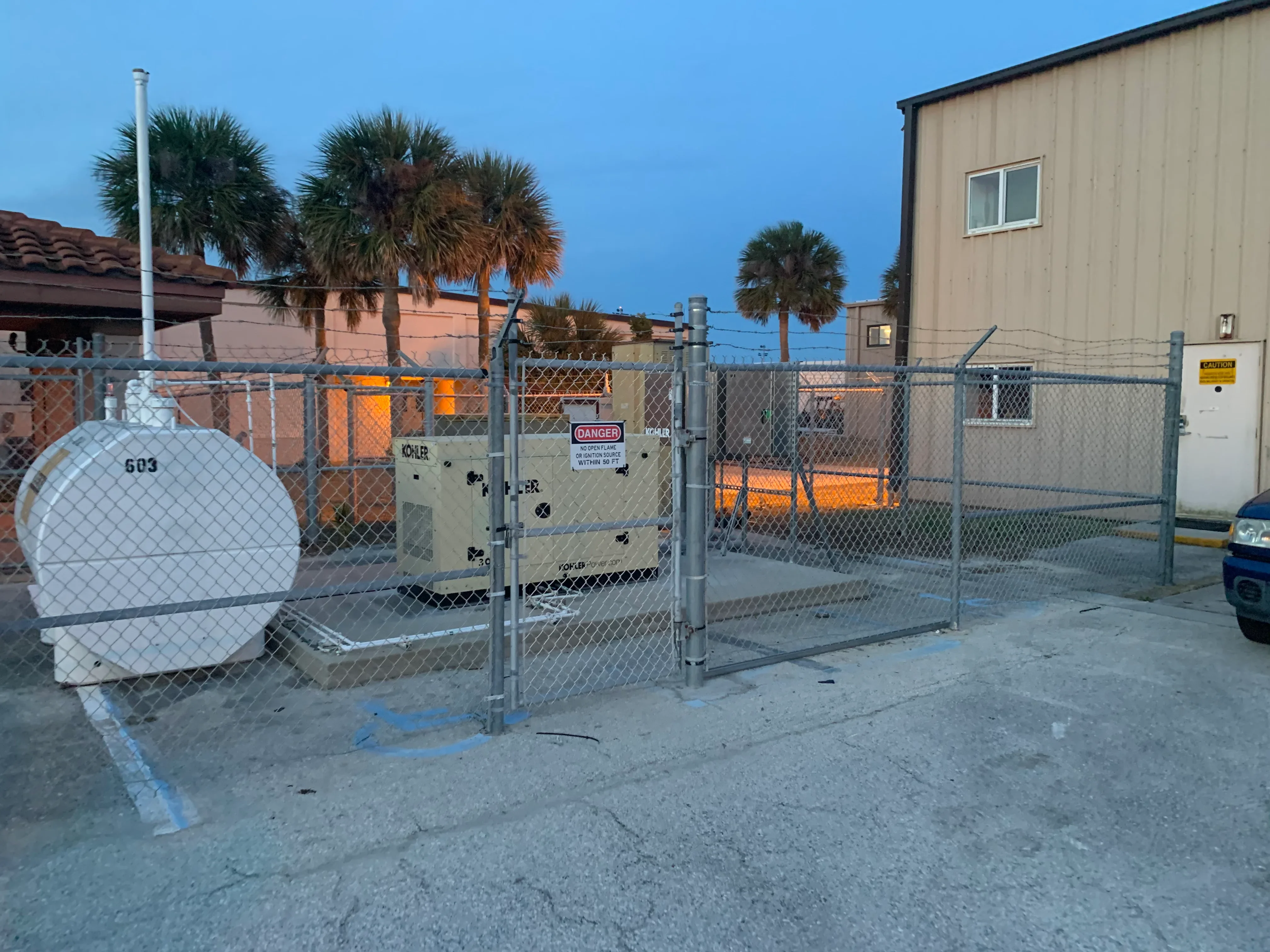 Industrial generator with chain-link fence enclosure and safety gate installation