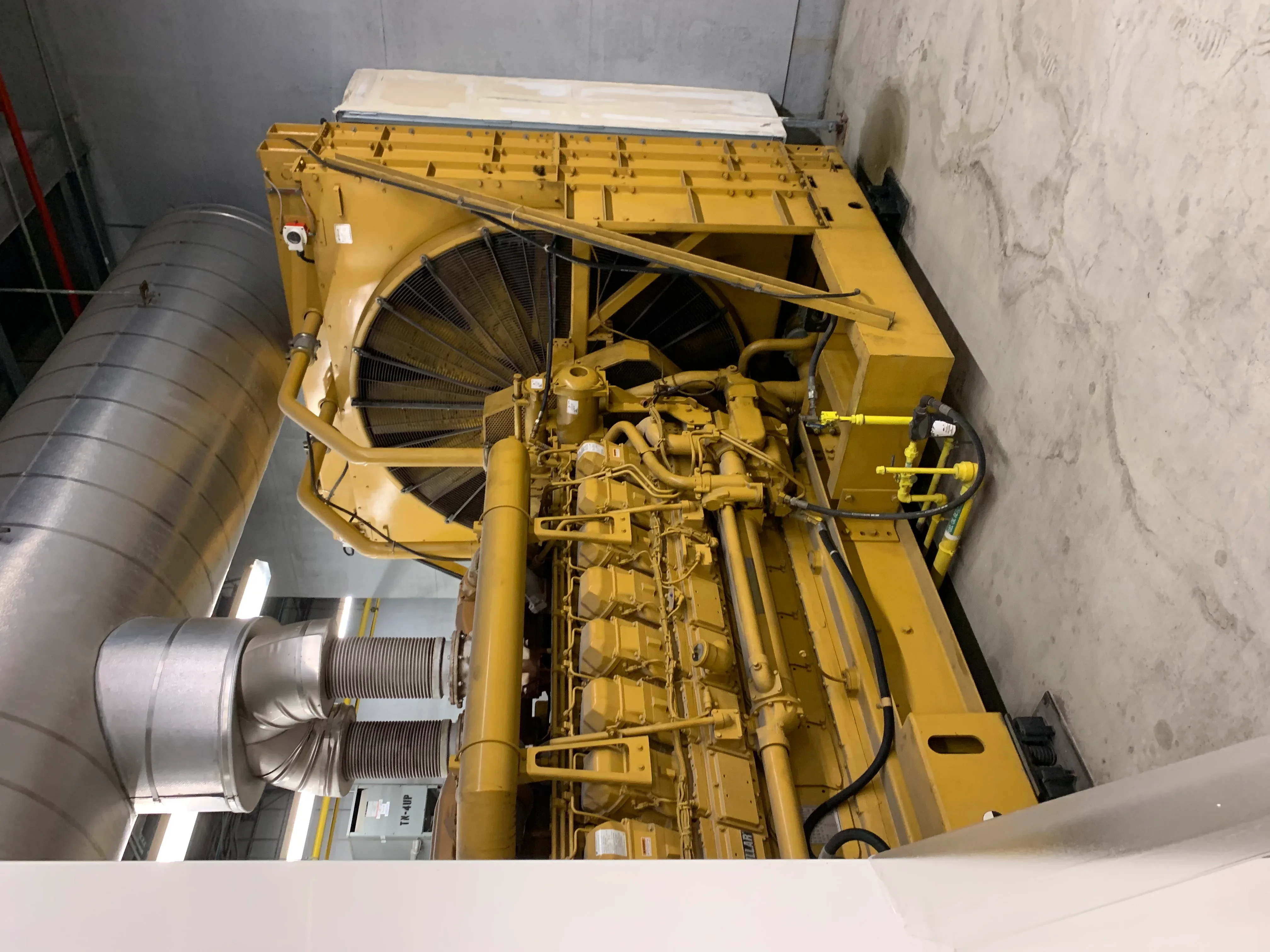 Industrial diesel generator engine with exposed cylinders, cooling fan, and electrical components during service