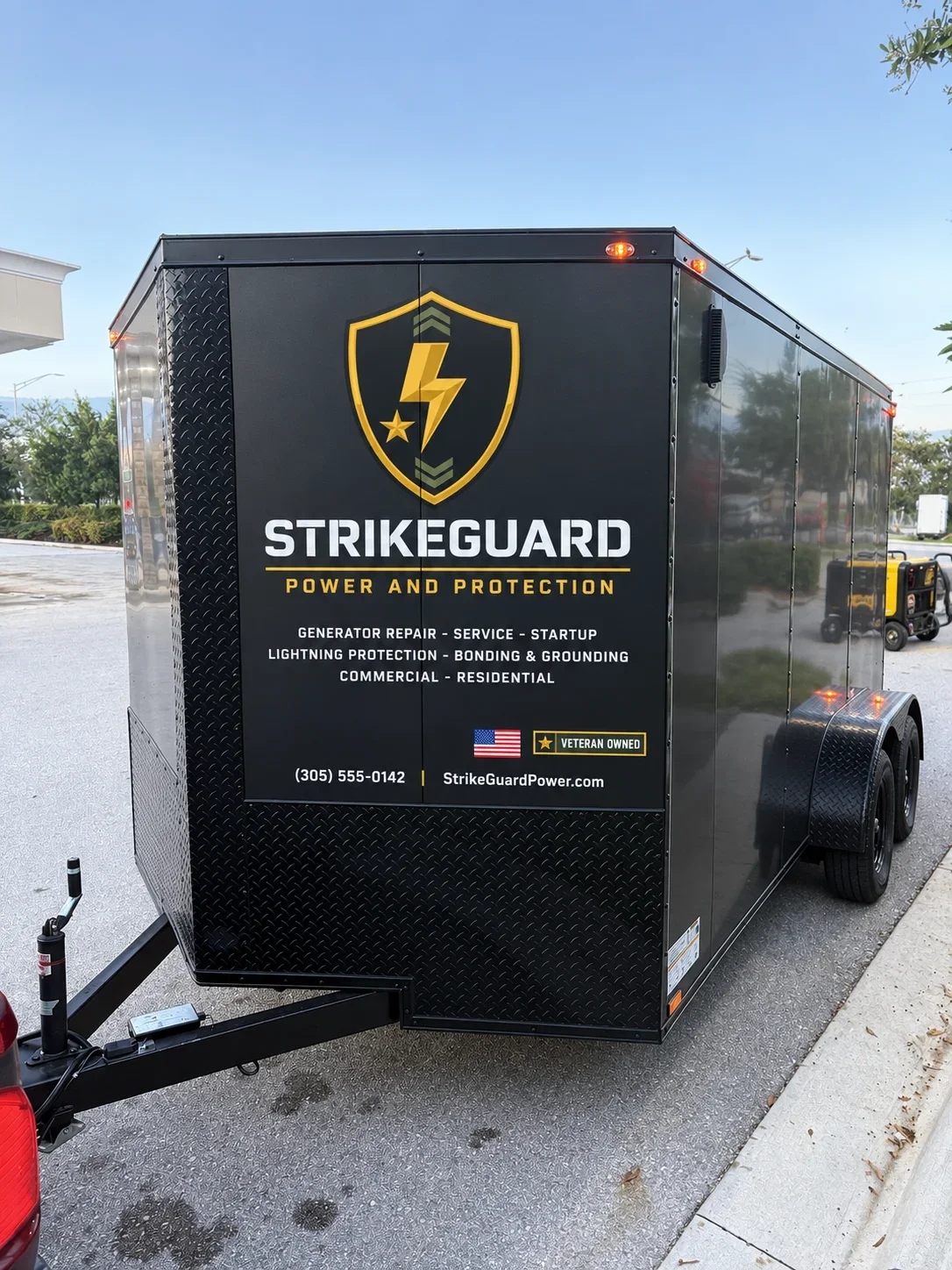 Black enclosed trailer with yellow and white StrikeGuard branding, diamond plate trim, and service details